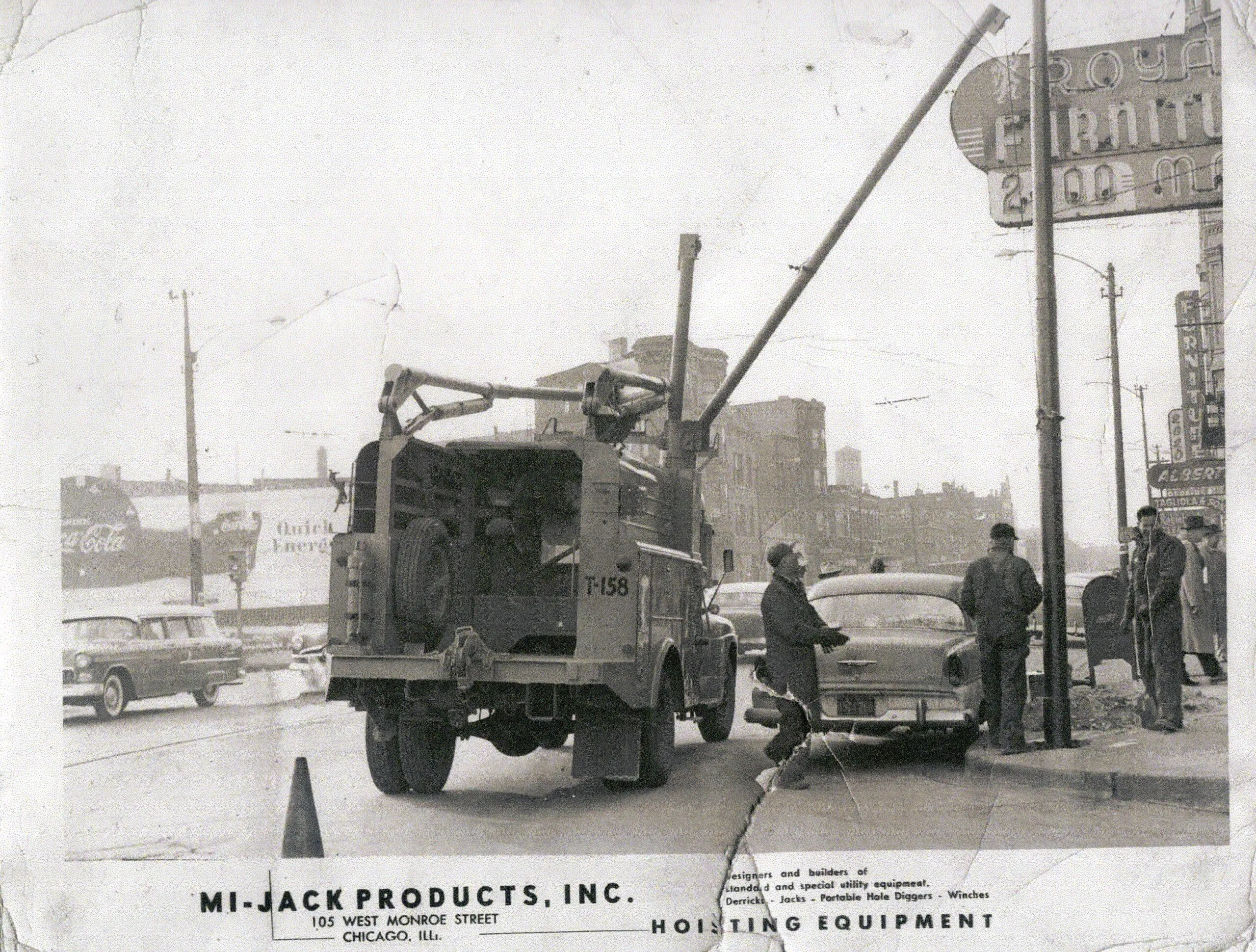 Demonstration of boom crane lifting utility poles over cars in 1954