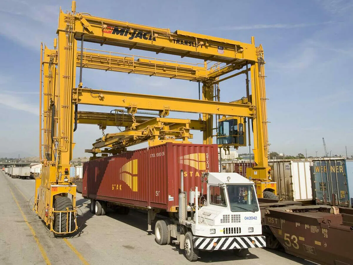 a red container under a yellow mj1200r translift crane