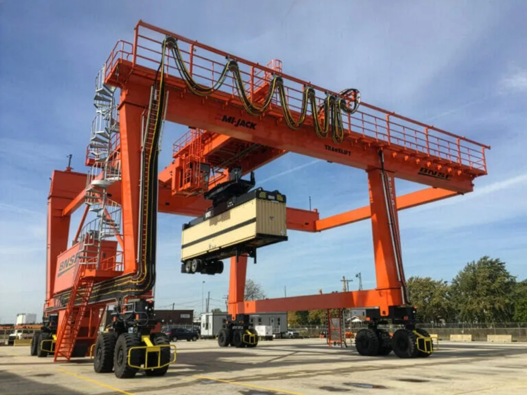an orange mj1400c cantilever rtg lifting white container
