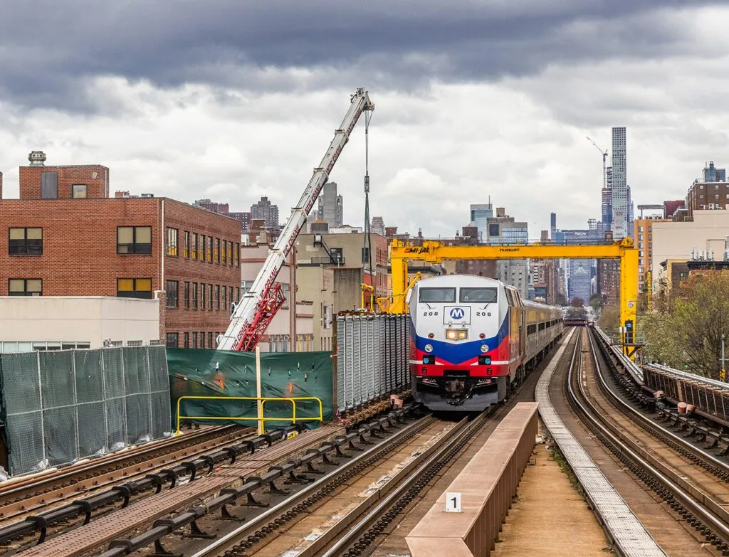 yellow mj300hd travelift against nyc skyline with train passing underneath